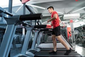 sportlicher junger Mann, der läuft und Musik von seinem Smartphone im Fitnessstudio hört foto