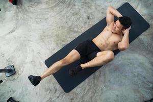 Sportlicher Mann, der Übung im Fitnessstudio trainiert foto