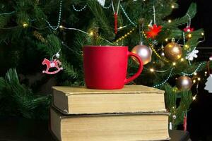 leer rot Becher mit Weihnachten Baum auf Hintergrund, Matte Tee oder Kaffee Tasse mit Weihnachten und Neu Jahr Dekoration, vertikal spotten oben mit Keramik Becher zum heiß Getränke, leer Geschenk drucken Vorlage foto