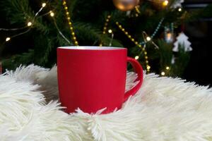 leer rot Becher mit Weihnachten Baum auf Hintergrund, Matte Tee oder Kaffee Tasse mit Weihnachten und Neu Jahr Dekoration, horizontal spotten oben mit Keramik Becher zum heiß Getränke, leer Geschenk drucken Vorlage foto