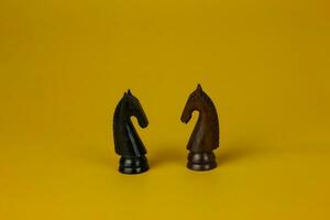 zwei Pferde gegenüber jeder andere zum Kampf und Schach Pferd Stück isoliert Gelb Hintergrund, benutzt zum Erfolg und Strategie Konzept foto