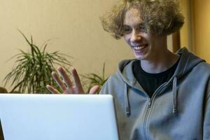 ein jung Kerl ist chatten im ein Video Plaudern über ein Laptop. Video Forderung. foto