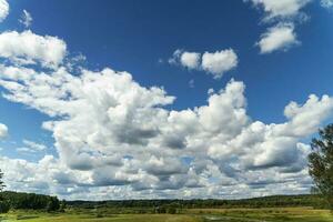 Hintergrund von ein Blau Himmel mit Wolken, ein Grün Feld, Fluss und Wald foto