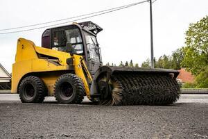 Reinigung von Müll von das Straße. ein rotierend mechanisch Maschine Bürste foto