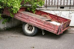 ein alt Auto Ladung Anhänger zum ein Passagier Auto geparkt Nächster zu das Haus foto