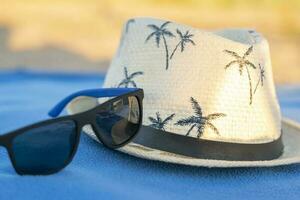 Sonne Hut und Sonnenbrille auf ein Strand Decke. Konzept von Sommer- Ferien foto