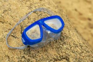 Kinder- Schwimmen Maske Lügen auf ein Stein auf das Ufer von das See foto