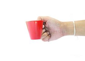 Mannhand, die kleine rote Kaffeetasse auf weißem Hintergrund hält foto