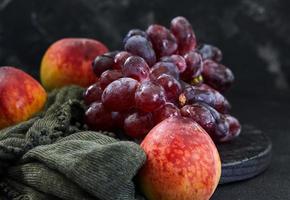 Trauben und Pfirsiche auf einem dunklen Hintergrund foto
