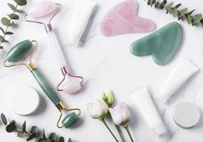 Cremetuben für kosmetische Produkte, Gesichtswalze und Eukalyptus auf Marmorhintergrund foto
