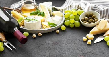 verschiedene Arten von Käse, Trauben, Wein und Snacks foto