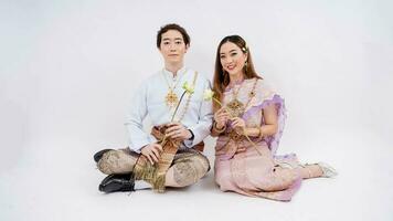 asiatisch Paar im traditionell thailändisch Kostüm halten Lotus und lächelnd isoliert auf Weiß Hintergrund, Thailand traditionell Kultur foto