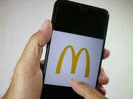 Jakarta, Indonesien, 2023. Hand halten Handy, Mobiltelefon Telefon mit Finger berühren das mc Donalds Logo auf Bildschirm. foto