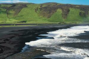 Landschaft von reynisfjara schwarz Sand Strand mit Grün Berg Angebot auf Süd Küste im Sommer- beim Island foto
