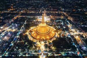 majestätische goldene pagode von phra pathom chedi, die zwischen den festlichtern rund um den kreisverkehr in der innenstadt von nakhon pathom leuchtet foto