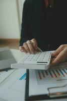 Unternehmerin, die einen Taschenrechner mit einem Stift in der Hand verwendet und die finanziellen Ausgaben im Home Office berechnet foto