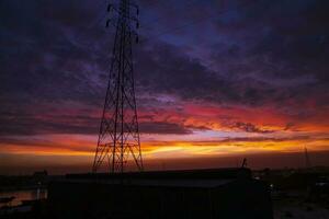 hoch Stromspannung Leistung Linie Turm mit schön Himmel beim Sonnenuntergang, Lager Foto