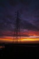 hoch Stromspannung Leistung Linie Turm mit schön Himmel beim Sonnenuntergang, Lager Foto