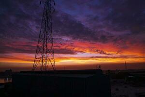 hoch Stromspannung Leistung Linie Turm mit schön Himmel beim Sonnenuntergang, Lager Foto