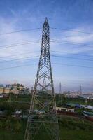 hoch Stromspannung Elektrizität Pylon mit Stadtbild und Blau Himmel Hintergrund. foto