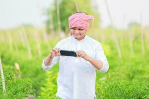 jung indisch Farmer zeigen Clever Telefon , Farmer reden auf Telefon im Bauernhof, glücklich indisch Farmer foto