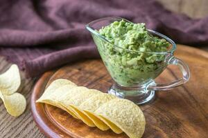 Guacamole mit Chips auf das hölzern Tafel foto