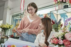 zwei jung schön weiblich Florist Partner diskutieren blühen Strauß Anordnung Design im Tablette, online Kauf bestellen Arbeit im bunt Blume Geschäft Geschäft mit frisch Flora, sme Geschäft Unternehmer. foto