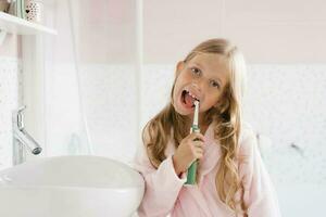 Kind Bürsten seine Zähne im das Badezimmer im das Morgen nach Schlafen. ein Mädchen mit Zahnpasta und ein Bürste. Dental und Oral Hygiene, Pflege. foto