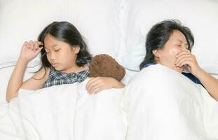 Mutter gähnen und schlafen mit ihr Tochter auf Bett, foto