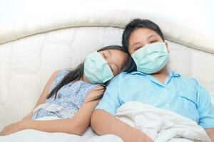 Bruder und Schwester tragen medizinisch Gesicht Maske Sitzung auf Bett beim heim, foto