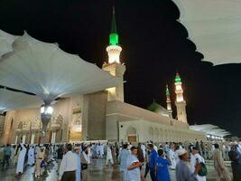 Medina, Saudi Arabien, kann 2023 - - schön Nacht Zeit Aussicht von Masjid al Nabawi, Medina. Besucher, Höfe draußen das Moschee, schön Beleuchtung und elektronisch Regenschirme können ebenfalls Sein gesehen. foto