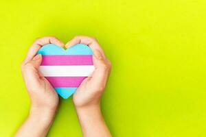 Frau hält im Hände ein Herz Farbe Flagge Transgender. foto