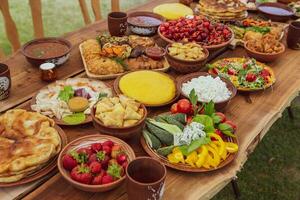 hausgemacht rumänisch Essen mit gegrillt Fleisch, Polenta und Gemüse Teller auf Camping. romantisch traditionell Moldawier Essen draußen auf das Holz Tisch. foto