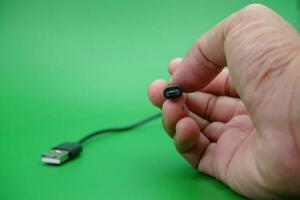 Hand halten USB Art ein zu USB Mikro b Kabel isoliert auf Grün Hintergrund. foto