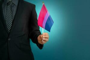 Geschäftsmann Hand halten Flagge im bisexuell Stolz Farben. foto