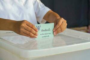thailändisch Menschen fallen ihr Abstimmung Papiere in das Box zu Abstimmung zum Mitglieder von das Haus von Vertreter. das Abstimmung Papiere sind geschrieben im thailändisch, Bedeutung Parteiliste proportional Darstellung Abstimmung Papier foto