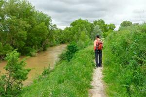 Frau Wanderer mit Rucksack auf das Pfad durch das Fluss foto