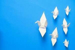 Weiß Vogel Origami Papier auf Blau Hintergrund. Vogel Frieden, Freiheit oder Chancen Konzept foto