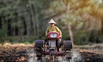 Bäuerin, die den Wandertraktor verwendet, um bei Regen für Reispflanzen zu pflügen foto