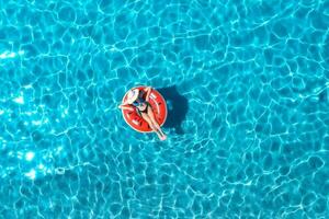 Antenne Aussicht von ein jung Frau Schwimmen mit rot schwimmen Ring foto