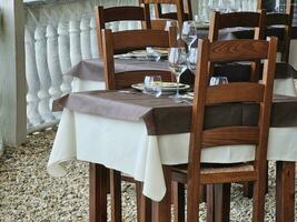 Tabellen und Stühle von ein Restaurant einstellen zum ein Sonntag Mittagessen auf das ligurisch Küste von varazze. während das Sommer- Ferien im Juni 2023 foto