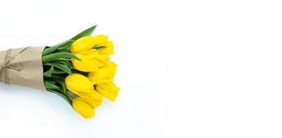 Strauß gelber Tulpen, eingewickelt in Kraftpapier auf weißem Hintergrund mit Kopierraum