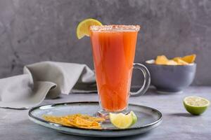 Michelada Cocktail mit Tomate Saft, Bier und Limette im ein Glas und Nachos foto