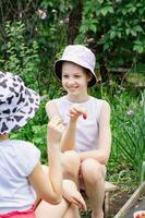 zwei Mädchen Show jeder andere gepflückt Erdbeeren im das Garten Vertikale Aussicht foto