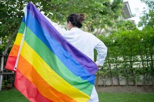 asiatische Dame, die Regenbogenfarbflaggensymbol des lgbt Stolzmonats hält, feiern jährlich im Juni soziales von schwulen lesbischen bisexuellen Transgender-Menschenrechten foto