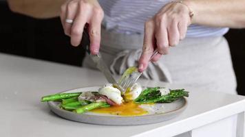 Frau, die mit Gabel und Messer Essen in weiße Schüssel schneidet foto