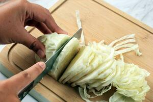 weiblich Hände Schneiden Weiß Kohl auf hölzern Tafel foto