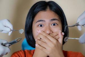 Mädchen, das von Zahnärzten verängstigt ist, bedeckt ihren Mund in der Zahnarztpraxis foto