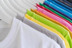Nahaufnahme von T-Shirts Kleidung auf Kleiderbügeln auf weißem Hintergrund foto