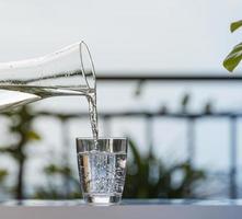 Gießen Sie im Gartenhaus Wasser aus der Flasche in ein Glas foto